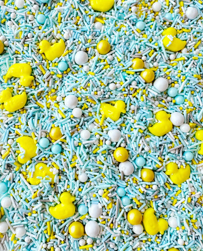 VARIETY SHAPED SPRINKLES INCLUDING DUCK SHAPED AND ROUND. YELLOW DUCK SPRINKLES WITH LIGHT BLUE WHITE AND LIGHT GREY SPRINKLES